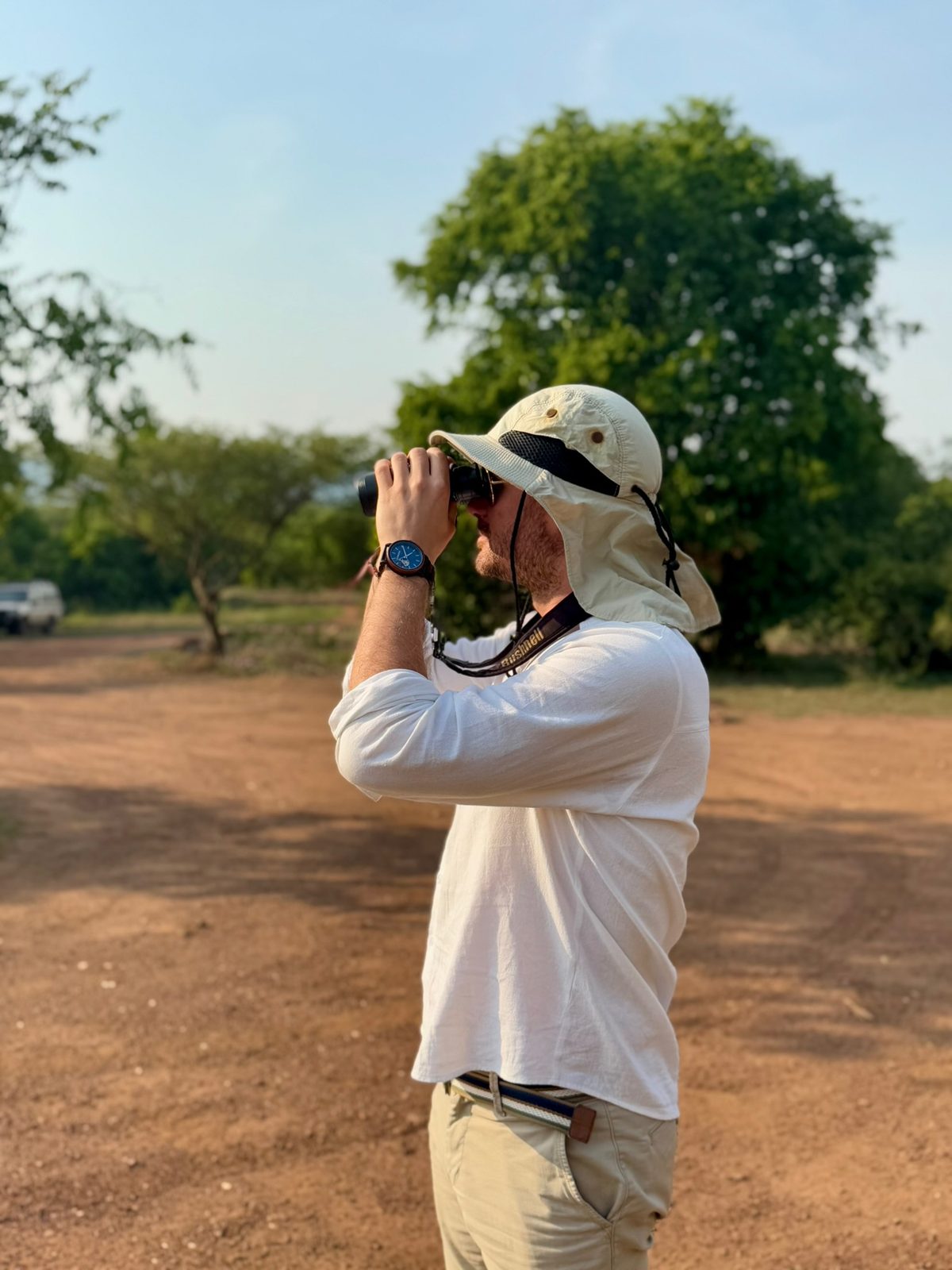 A guest scanning the plains with binoculars on safari
