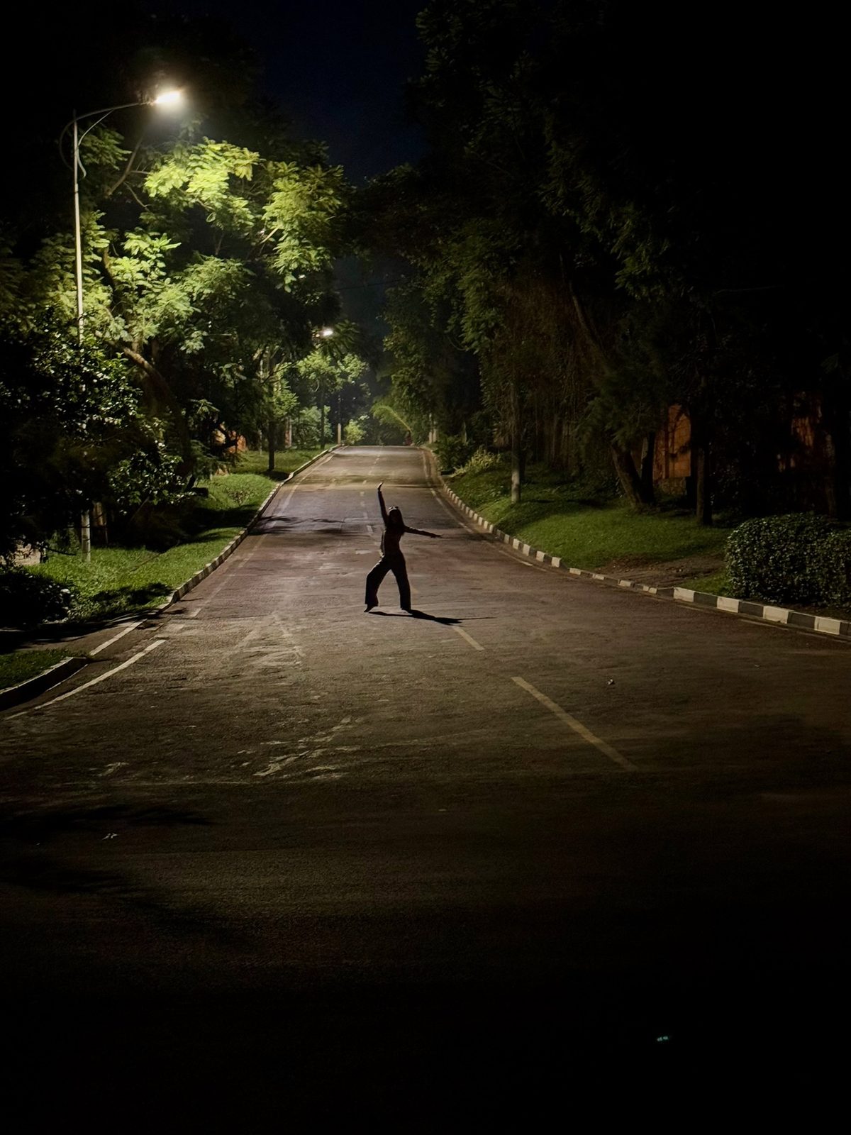 Dancing on a quiet tree lined road at night, Rwanda
