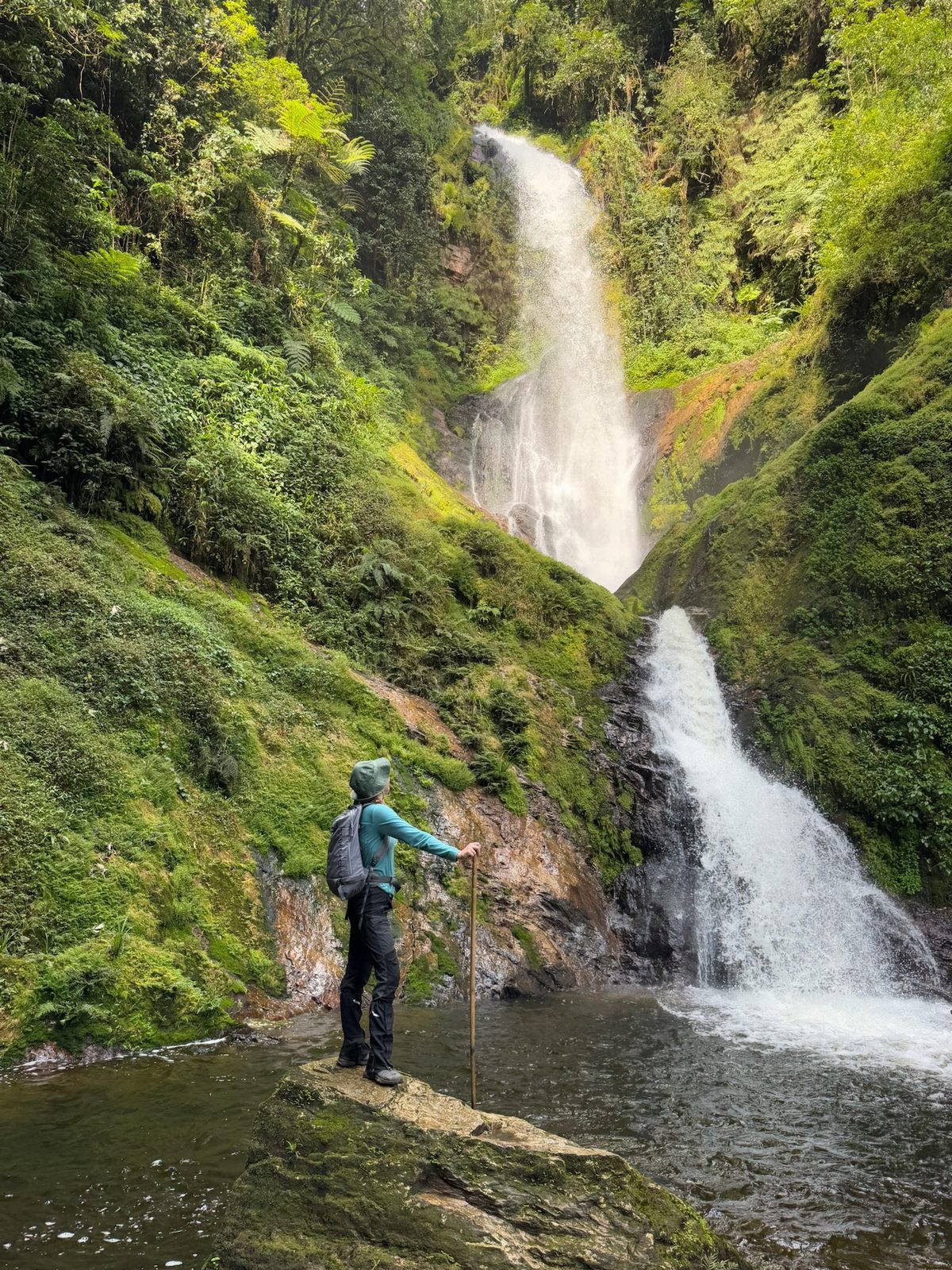 A guest at a waterfall on a forest hike, Rwanda